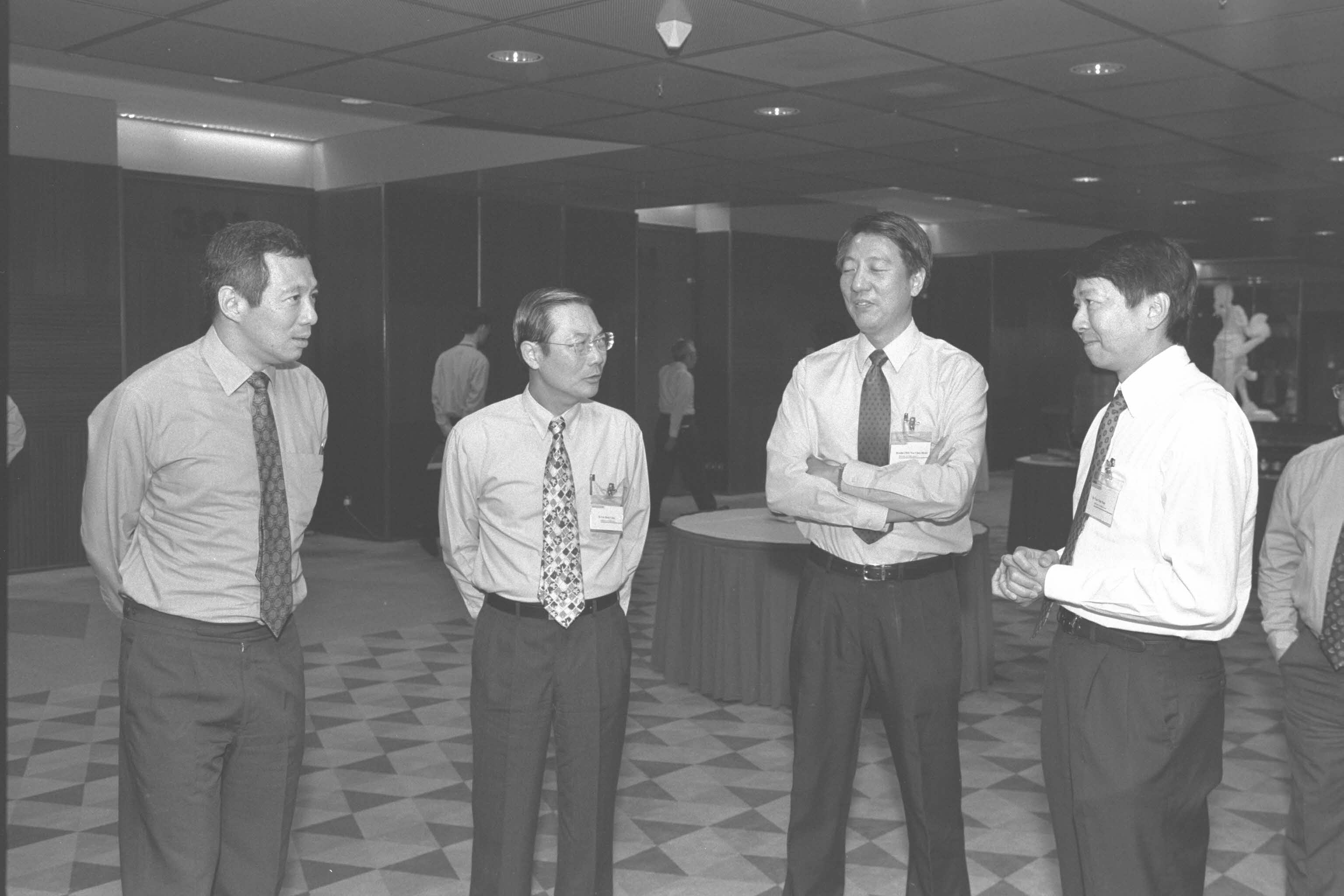 Image shows four men standing in a room. 