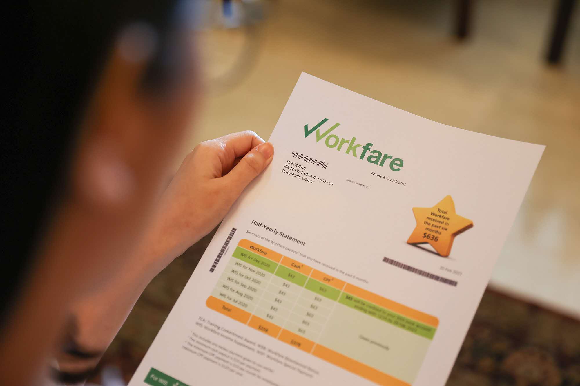 Image shows a person holding a sheet of paper.  